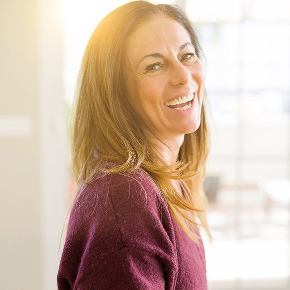 Woman in maroon sweater smiling with sunny background